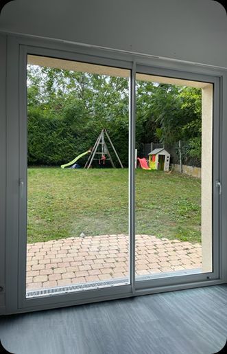 Baie vitrée coulissante en aluminium donnant sur un jardin